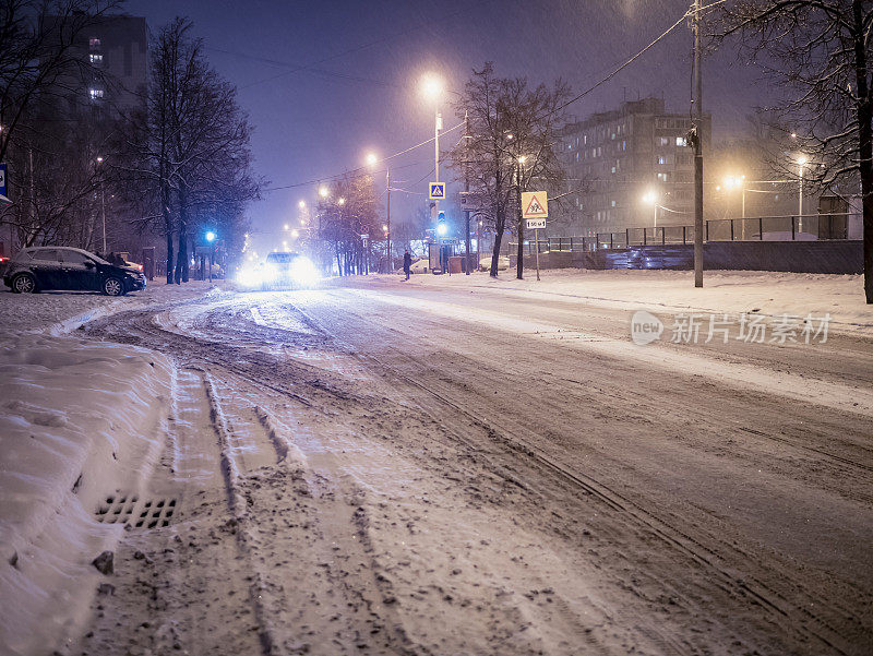 夜晚冬天下雪的城市道路与汽车擦肩而过