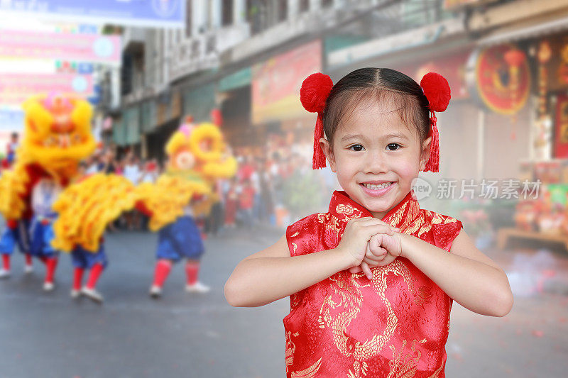 中国小女孩穿着中国传统的旗袍，在春节里为你祝福。