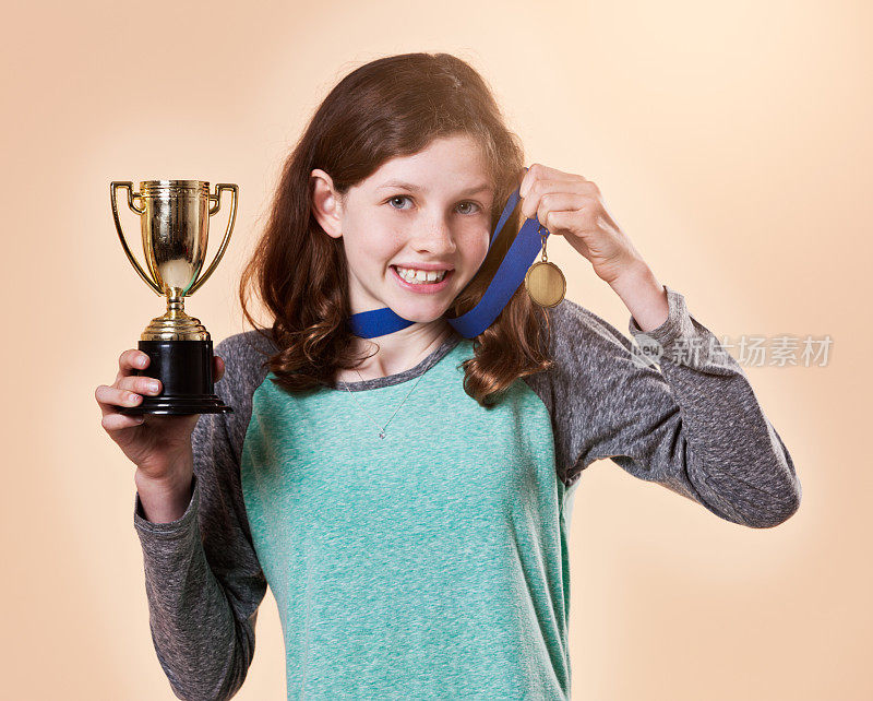 微笑的少女取得了胜利，佩戴着奖章，手持奖杯