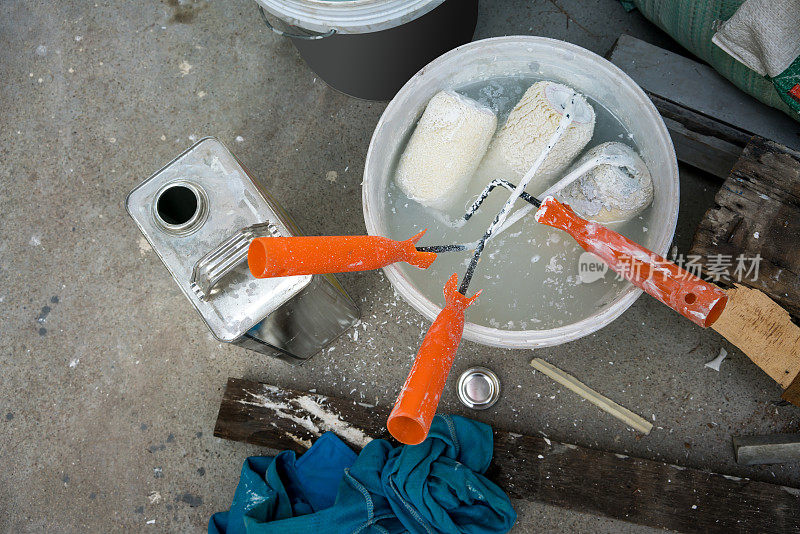 房屋装修施工现场用过的漆辊和漆刷浸泡在塑料色桶中。
