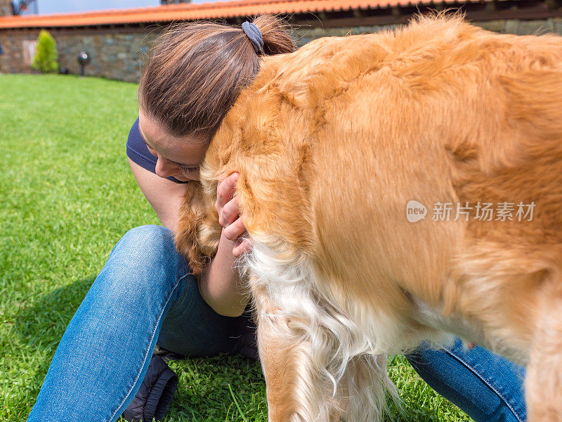 年轻女子在户外拥抱她的金毛猎犬