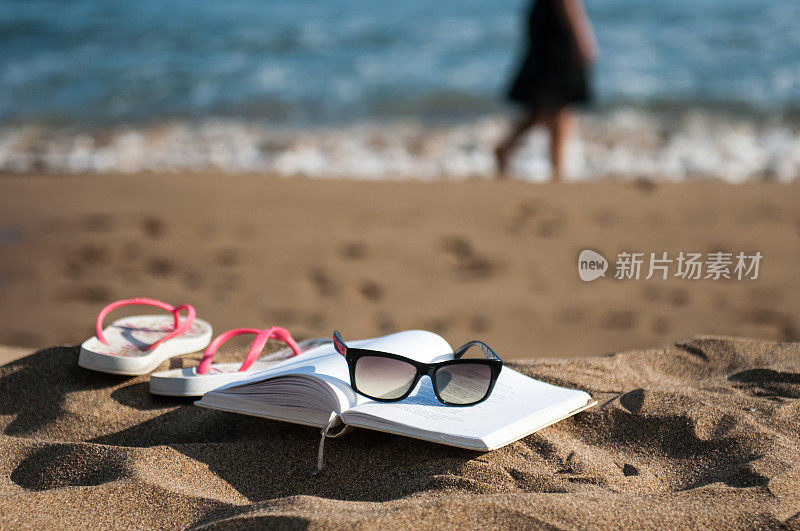 概念夏天的场景在海滩上打开书和一个女孩在海边散步