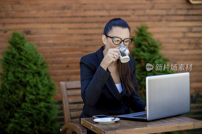 年轻的女商人在café用笔记本电脑工作