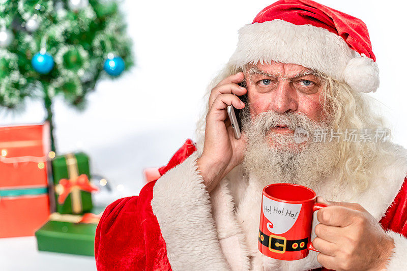愤怒的圣诞老人看着摄像头，用智能手机