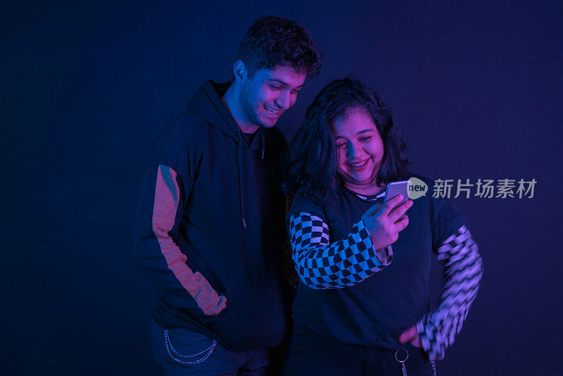 年轻夫妇在霓虹灯下使用手机