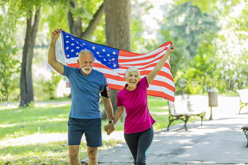 在公园里举着美国国旗的老夫妇