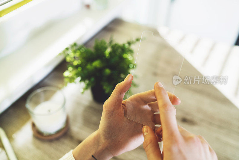 一个手持未来智能手机的女人，用一根手指按在玻璃屏幕上