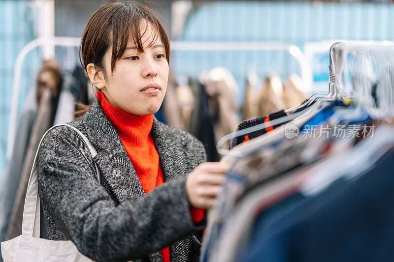 在户外二手商店挑选衣服的女人