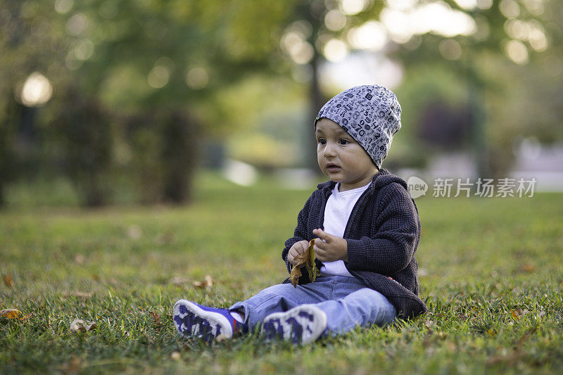 漂亮的男孩正坐在草地上。快乐的童年。孩子们在《自然》杂志上。