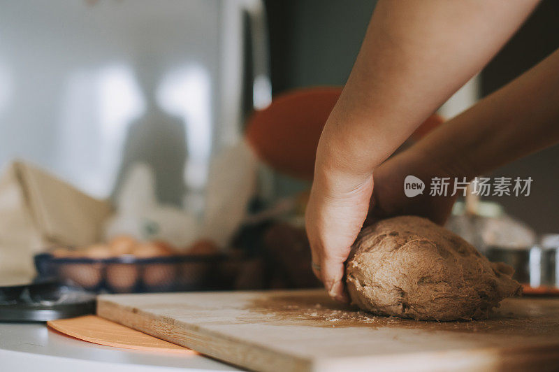 一个亚洲华人呆在家里的母亲在厨房里准备面团