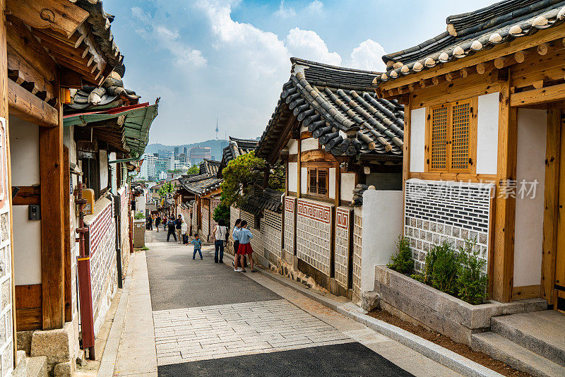 在韩国首尔的北川韩屋村，游客们穿着传统的韩服走在历史悠久的韩式街区