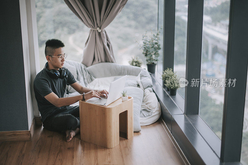 一个亚洲的中国少年男孩在家上学，在卧室里用笔记本电脑学习