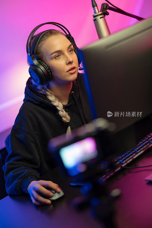 专注于专业电子竞技游戏玩家女孩，头戴耳机在PC上玩在线视频游戏