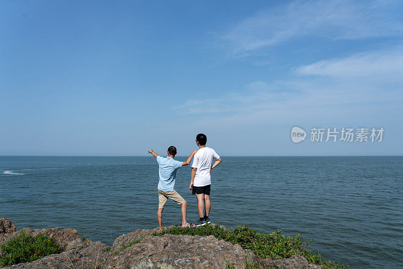 两个男游客在看海边的风景。