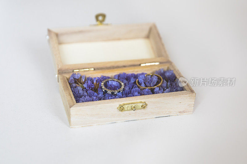 结婚戒指放在一个用紫色花朵装饰的小木盒里
