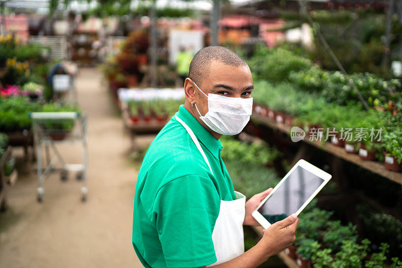 花商戴着口罩在花店使用平板电脑的肖像