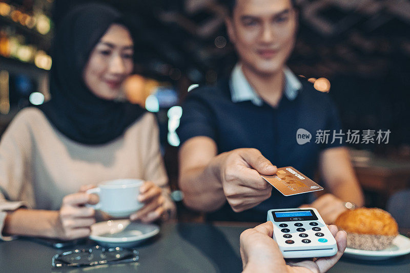 亚洲人种男子给信用卡在咖啡馆非接触式支付
