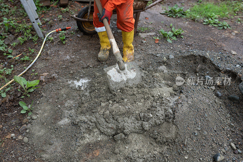 老建筑工人在现场用铲子搅拌混凝土、水泥和沙子