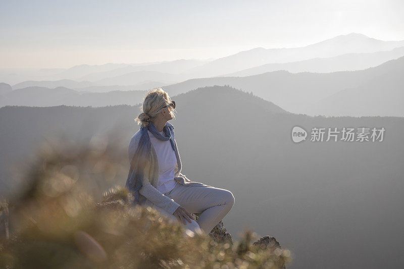 清晨，女徒步旅行者在阳光明媚的山脊上放松