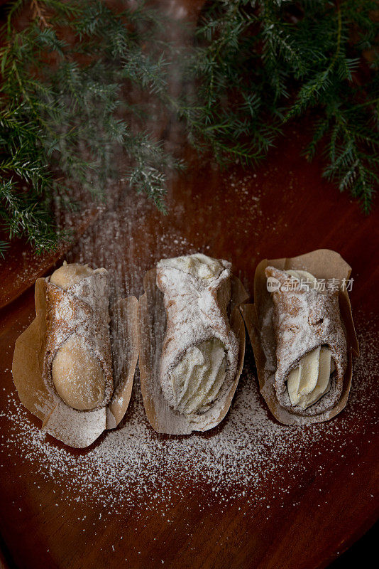 圣诞餐桌-糖霜粉落在奶油煎饼卷上，红木托盘装饰针叶树的树枝