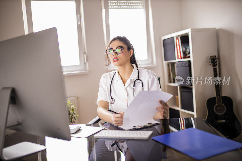 疲惫的年轻女医生检查医疗文件和使用电脑在她的办公室