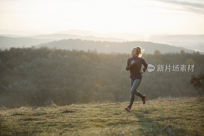 年轻的女运动员在山上跑步。