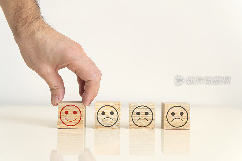 商人选择一个微笑表情符号的图标脸快乐的象征上的木块，服务和客户满意度调查的概念