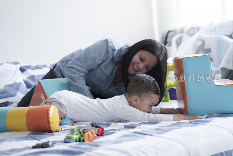 一位年轻的母亲和她两岁的儿子在床上玩他的益智玩具。