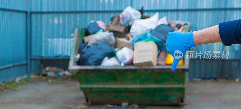 一名男子戴着橡胶手套收集垃圾。容器里有很多垃圾。垃圾崩溃。门卫的罢工。塑料回收的环境灾难。和特写