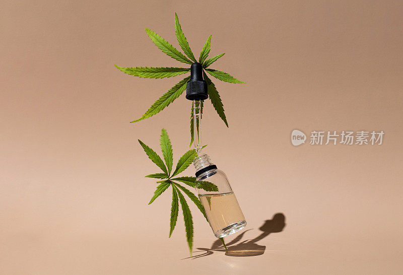 米色背景上装有CBD油，THC酊剂和大麻叶子的瓶子。替代化妆品医学概念