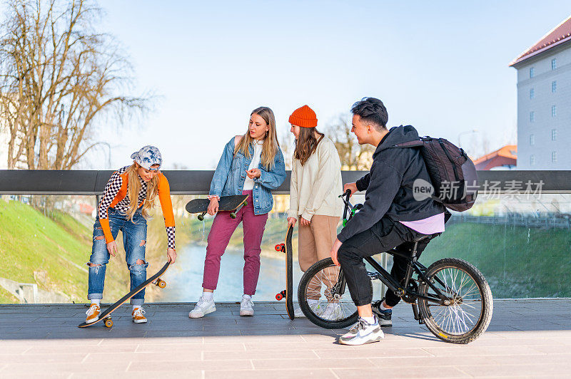 年轻的朋友们在桥上玩滑板和小轮车