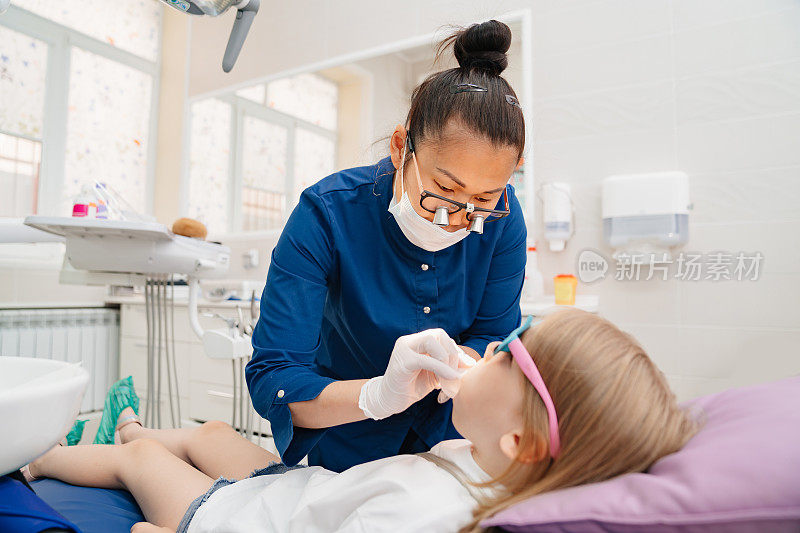 牙医在检查一个小女孩的嘴。