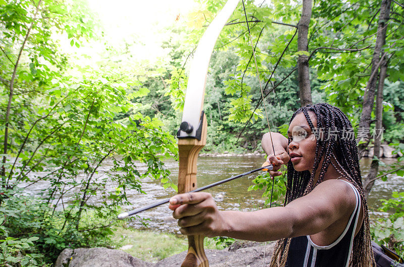 年轻的海地女人正用弓箭瞄准目标