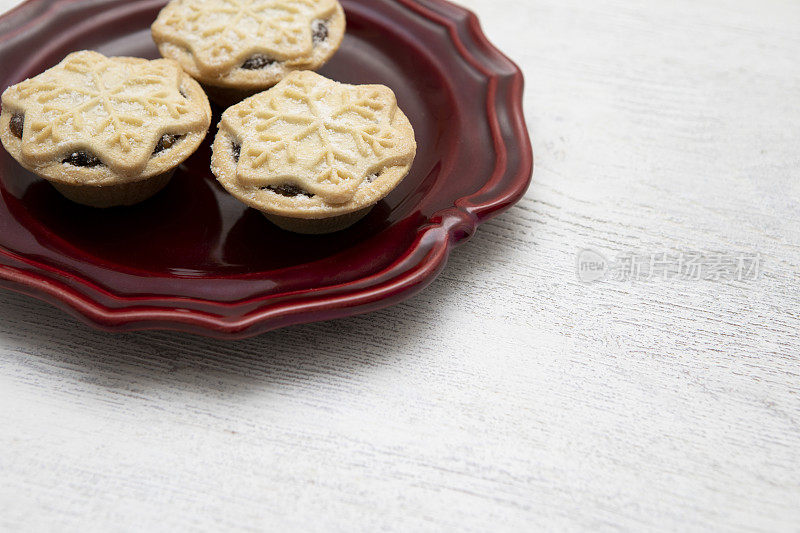 三个雪花装饰的碎肉馅饼放在红色复古风格的盘子上，有复印空间