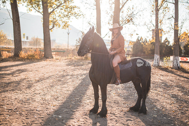 美丽的年轻女子骑着马，在大自然中度过一个阳光明媚的秋日