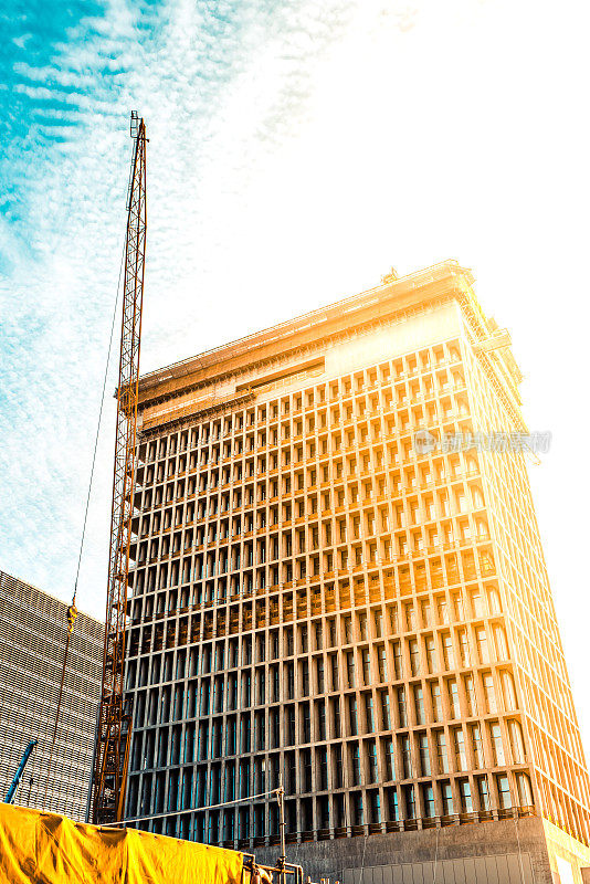 建筑工地，夕阳下脚手架上建筑工人的剪影。