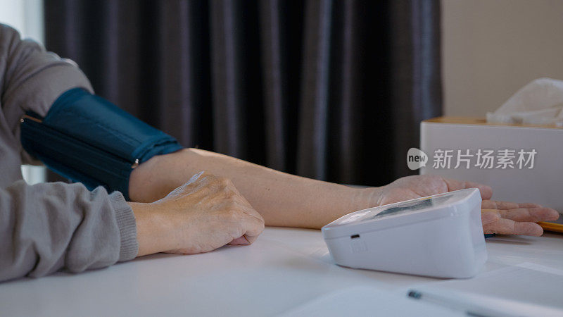老人在家里用笔记本记录自己的血压，用手检查血压。数字脉冲检测设备