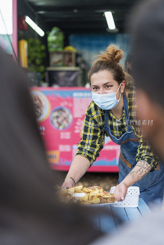 一名餐车女服务员将食物送到顾客的餐桌上。