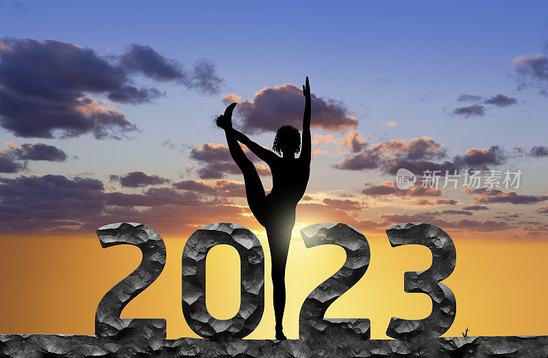 2023年新年快乐，女性在日落时练习瑜伽的剪影