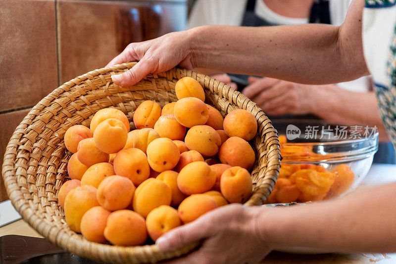 两代妇女在家里用新鲜的有机杏准备杏酱