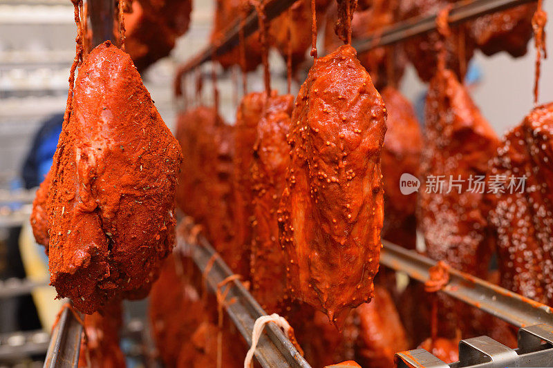 在肉类加工厂或肉店里，用辣椒粉和香料制成的美味猪肉挂在金属架子上。