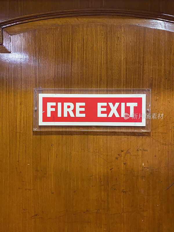 紧急防火门上的矩形红色和白色“消防出口”标志的特写图像，重点关注前景