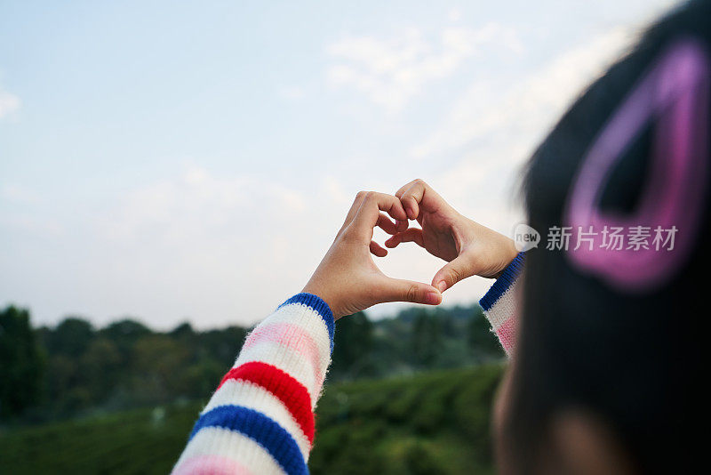 周末在山上旅行时，蹒跚学步的女孩在她的手上做心形符号