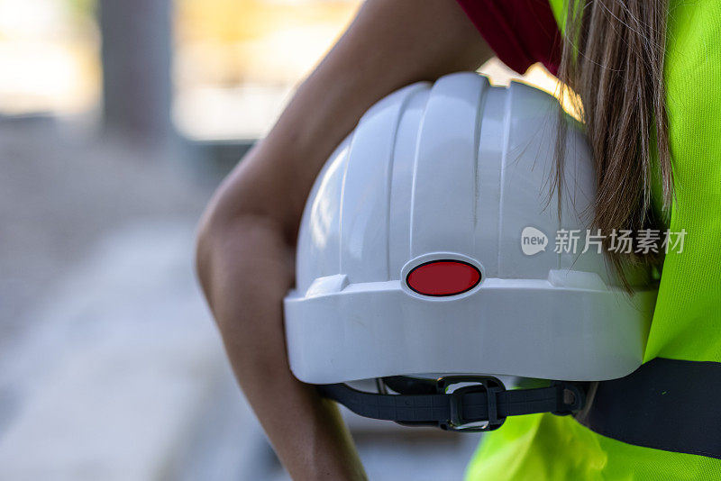 女建筑工人在工地手持防护头盔。