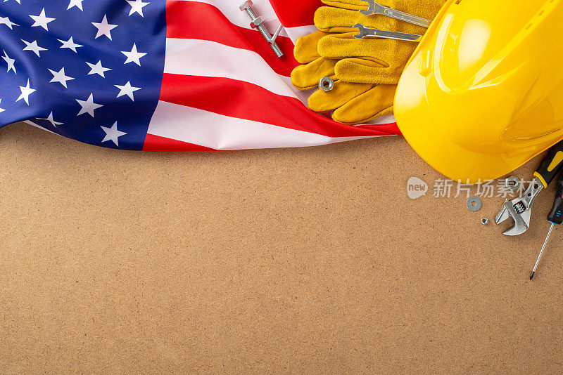 五一建设主题。美国国旗俯视图，工人工具，头盔，扳手，螺丝，螺母，手套，螺丝刀，活动扳手。胶合板背景，建筑公司标志的空白空间