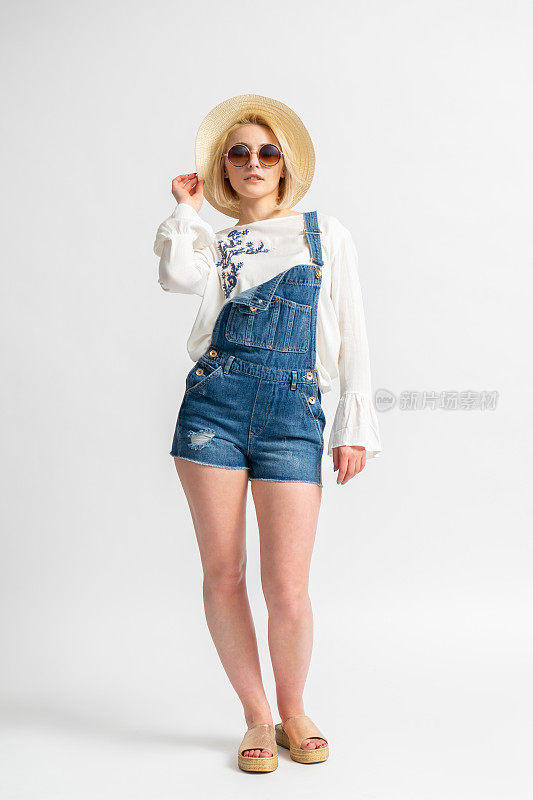 女士穿着休闲的夏季牛仔短裤，乡村衬衫，草帽和太阳镜