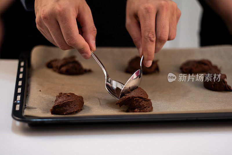 一个人把饼干面团放在烤盘上的特写