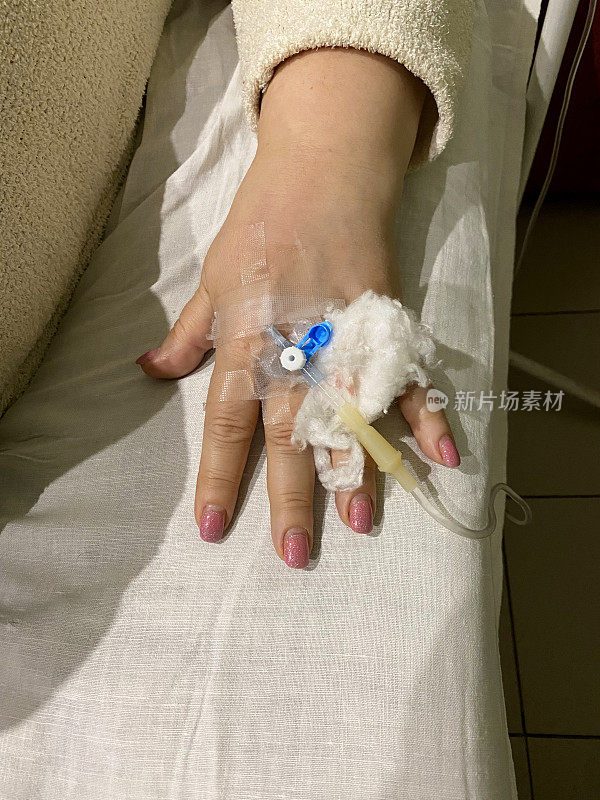 女性的手拿着连接在一起的医用滴管针。