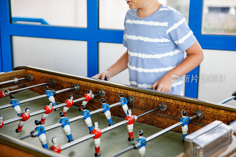 小男孩踢桌上足球的特写。快乐兴奋的孩子与兄弟姐妹或朋友玩家庭游戏的乐趣。积极的孩子。