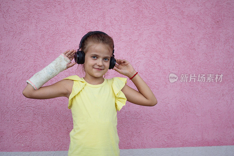 微笑的可爱小女孩的肖像，戴着破碎的耳机